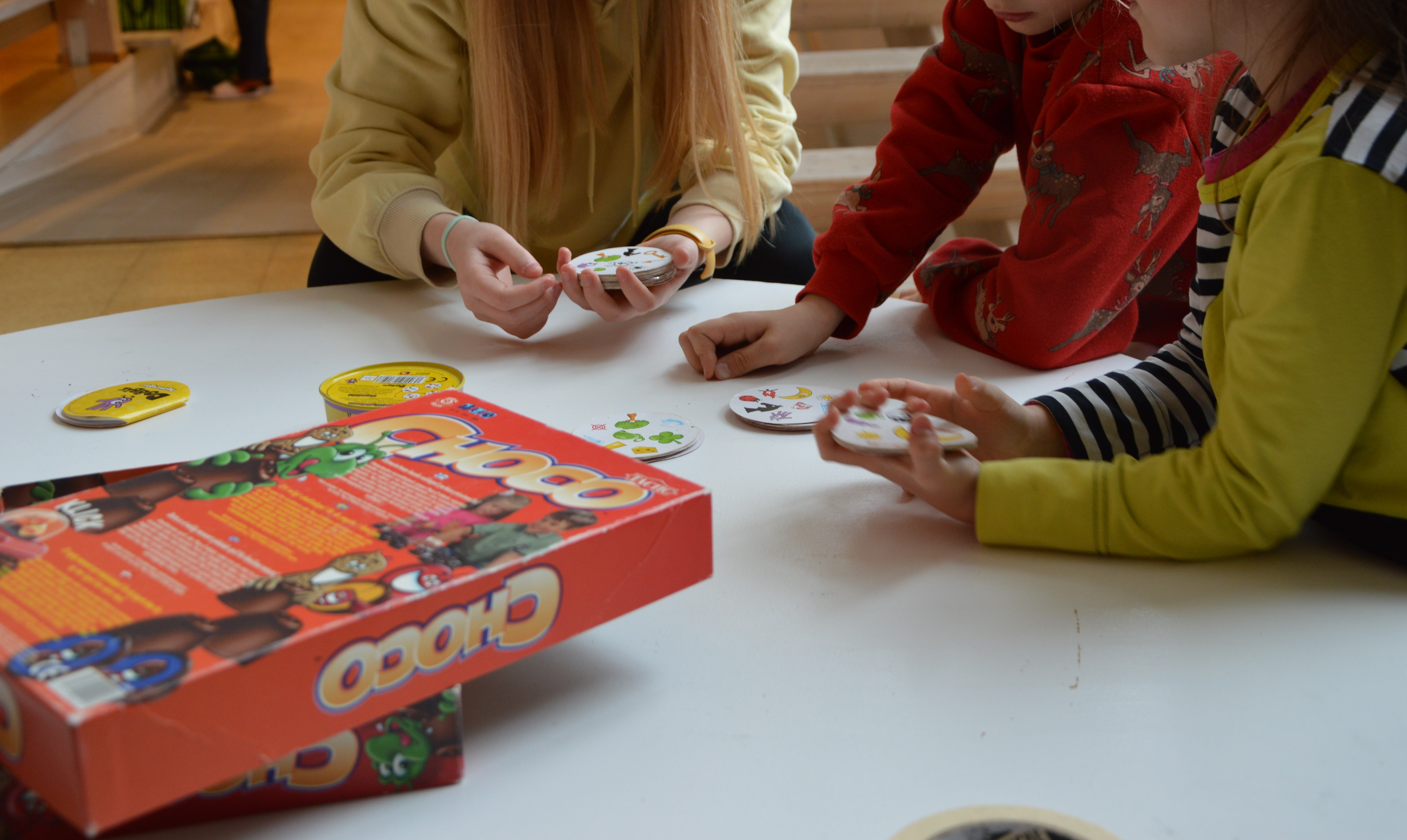 lapset pelaavat Dobble-peliä pöydän ääressä