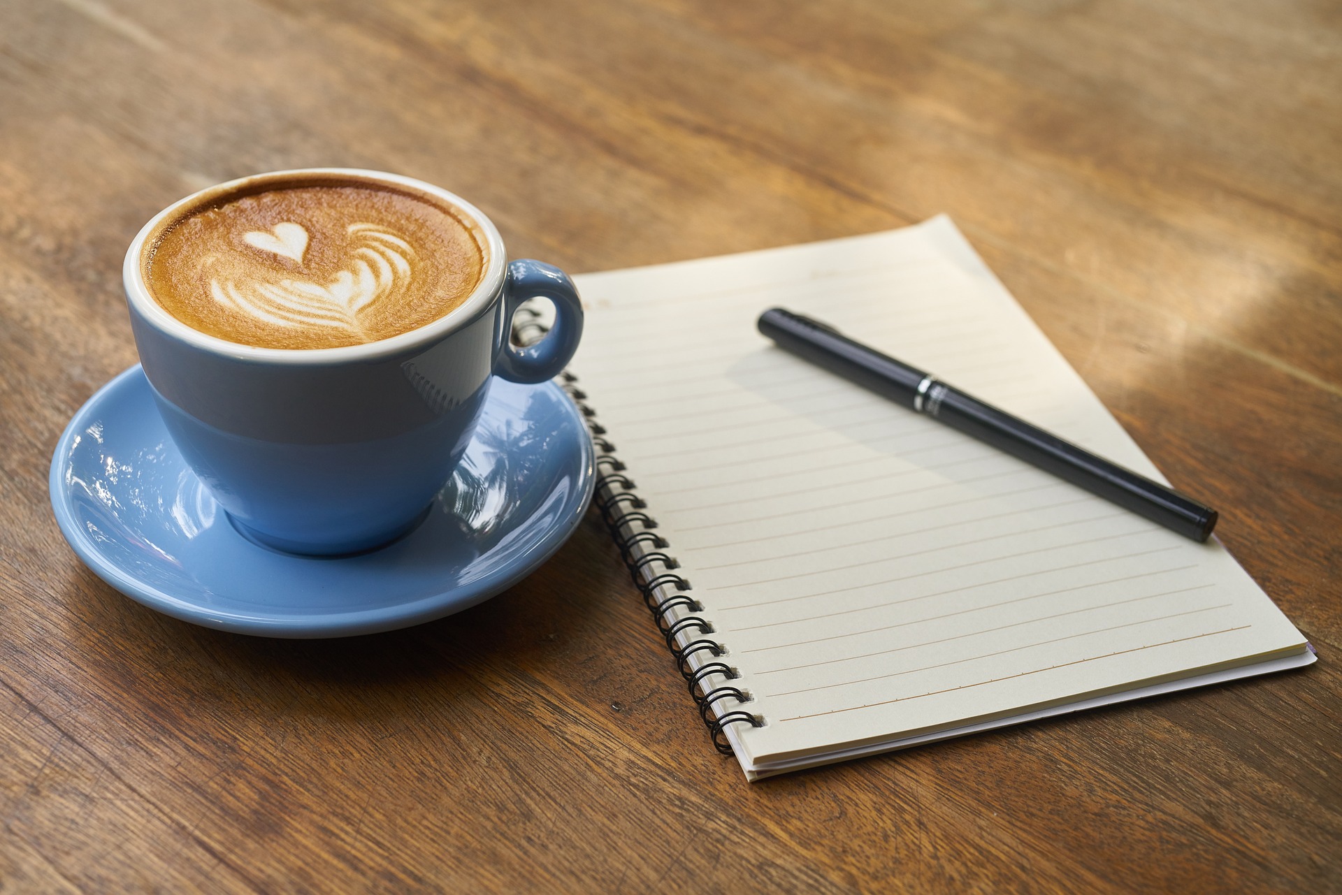 Kahvikuppi ja muistilehtiö kynällä